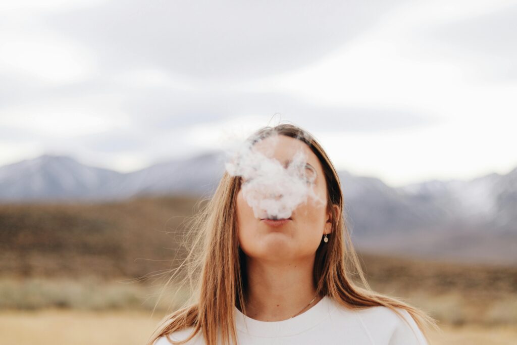Woman exhaling vapor outdoors representing inhalant addiction and substance use risks in Fresno, California.