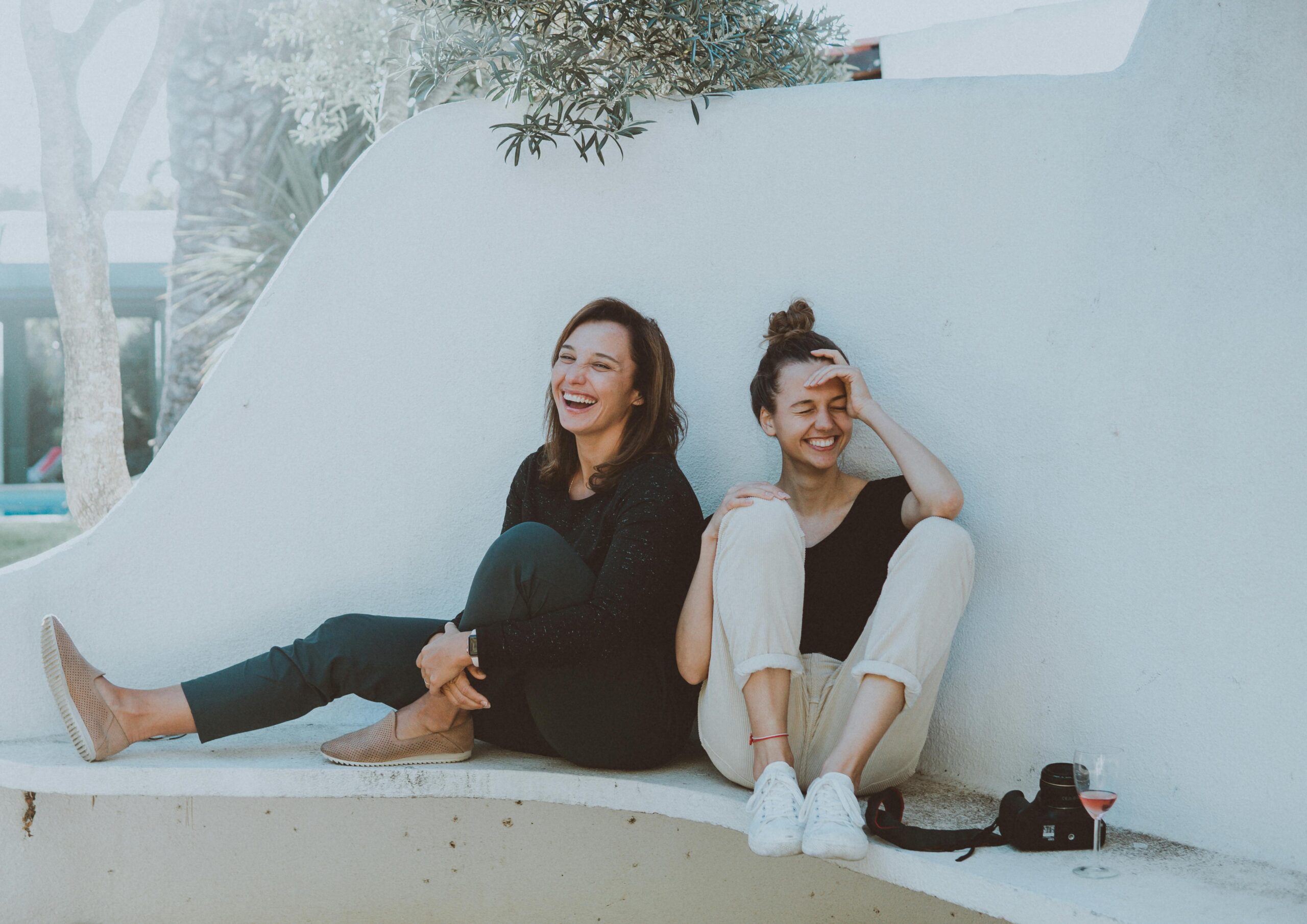 Two Women smiling and happy sitting against the wall on the ground for My Time Recovery located in Fresno