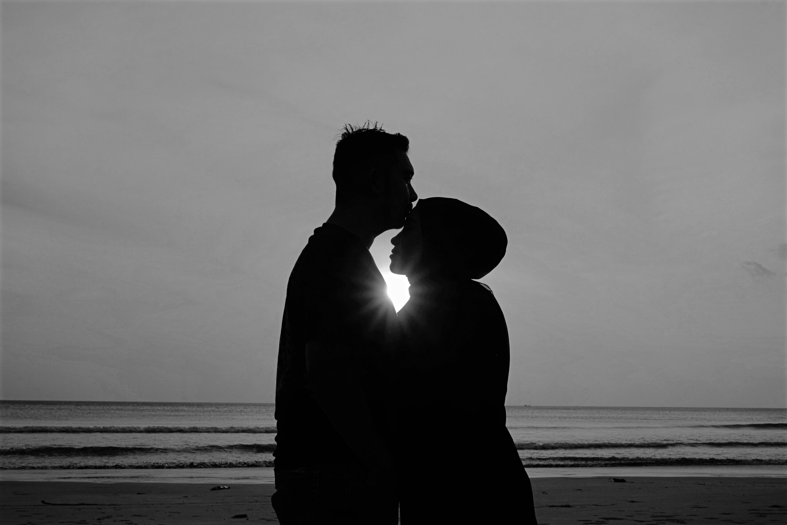 Loving couple hugging each other infront of the ocean during sun set. One of people suffer with depression.