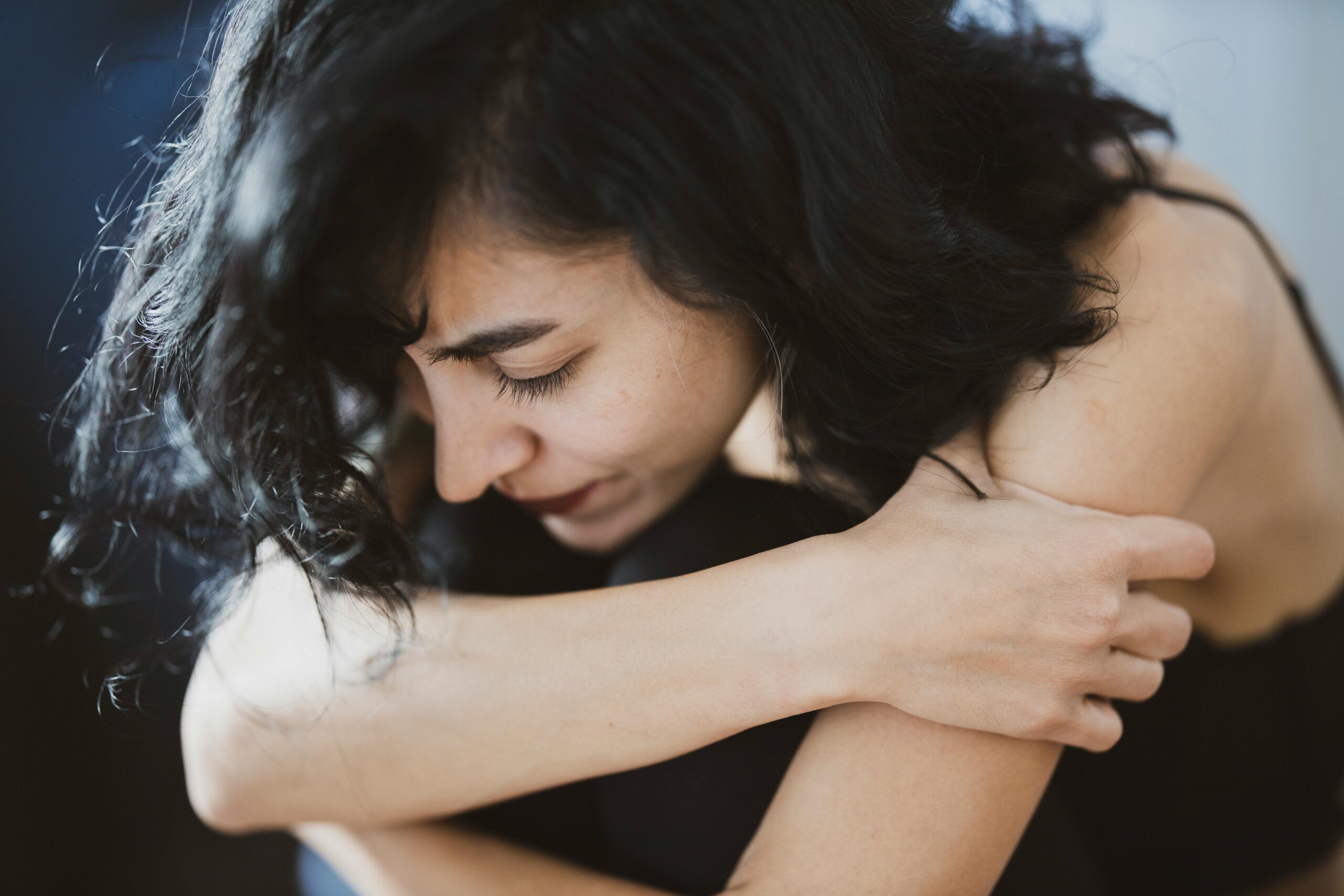 Close up of a woman holding herself struggling with getting mental health treatment in Fresno, California.