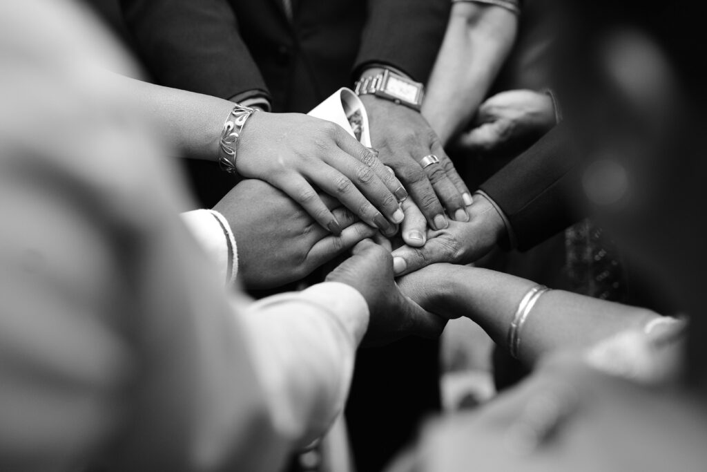 Black and white photo of a close up of hands together in a circle symbolizing support during recovery in Fresno, CA.